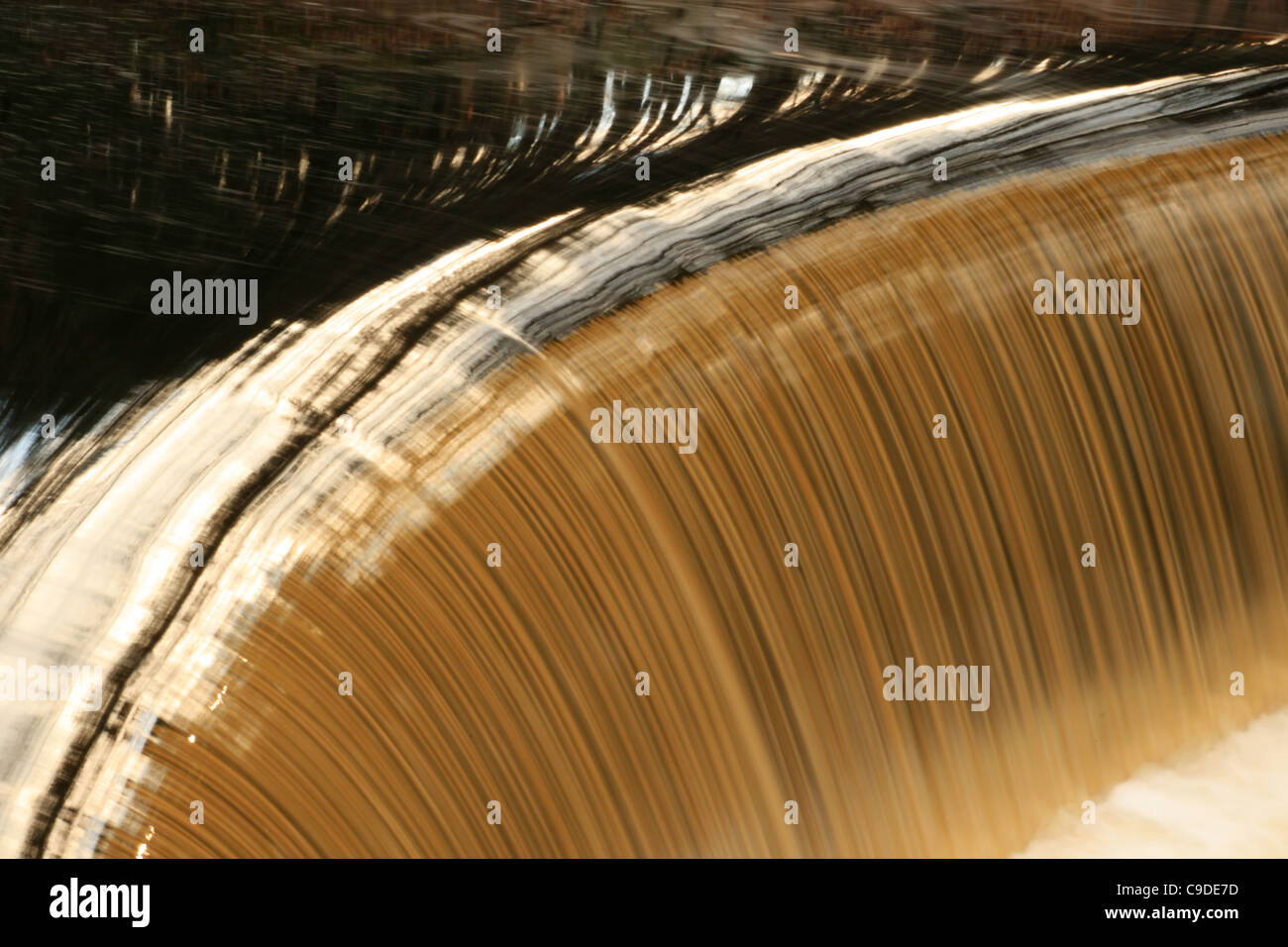 Il colorato marrone Charles River versa su una bassa diga curvo in una lunga esposizione Foto Stock