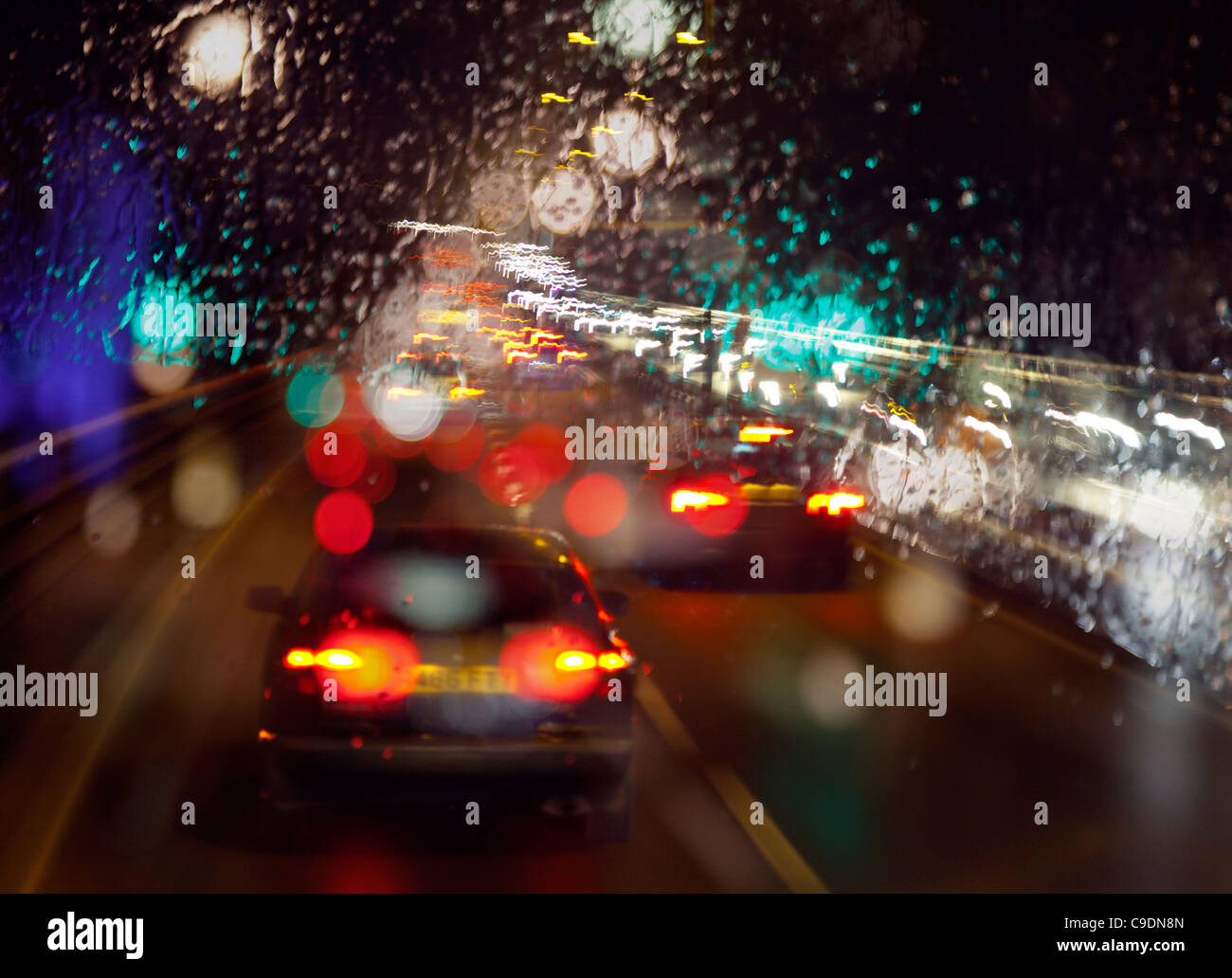 A tarda notte pioggia umido sul parabrezza in condizioni di scarsa visibilità durante la guida fuori Londra in sera Rush Hour nel traffico pesante Foto Stock