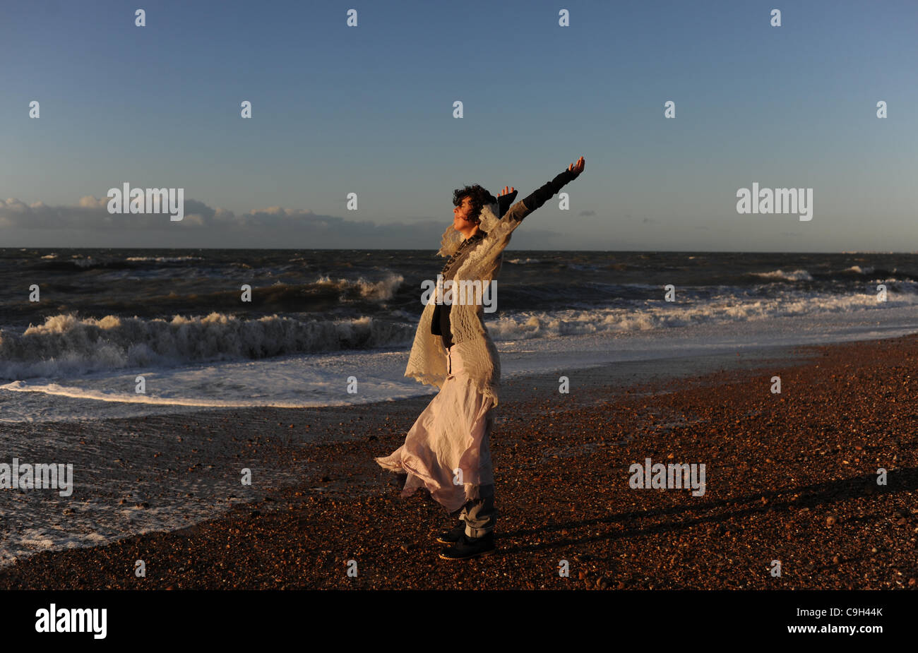 Una giovane donna rende la maggior parte della bellissima alba sulla spiaggia di Brighton dal Molo Ovest a bordo di mare Foto Stock