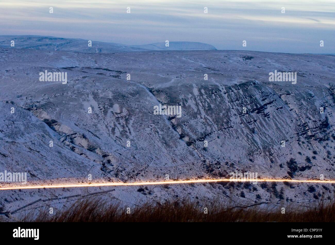 4 febbraio, 2012. Fari di automobile facendo una scia di luce come essi testa attraverso la coperta di neve Brecon Beacons vicino a piani di bracci sulla strada principale per la piccola città Brecon in Galles centrale stasera. Foto Stock
