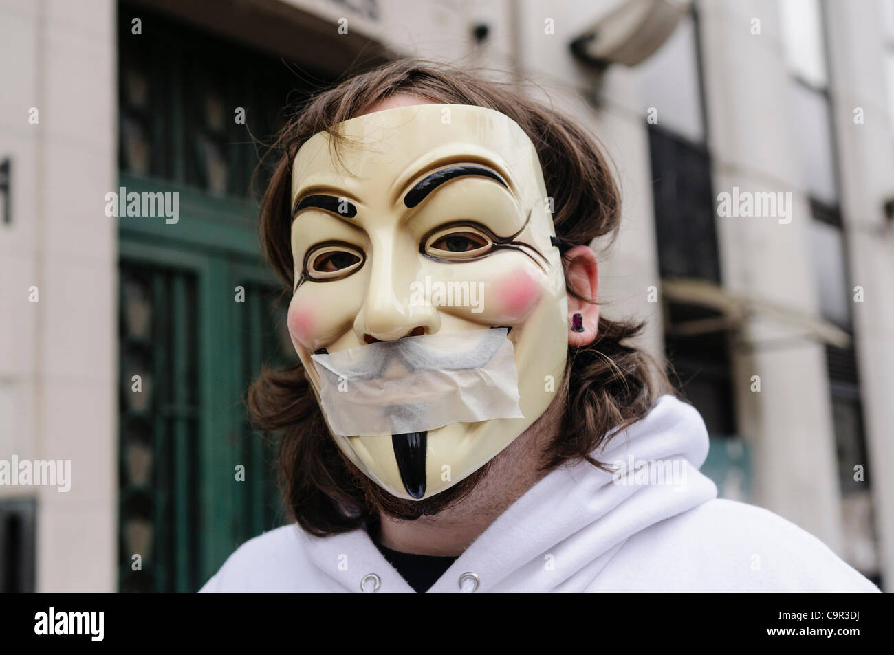 Membro del gruppo di hacker 'anonimo' indossando un 'V per Vendetta" maschera e il nastro sopra la bocca a significare la censura e limitazione della libertà di parola Foto Stock