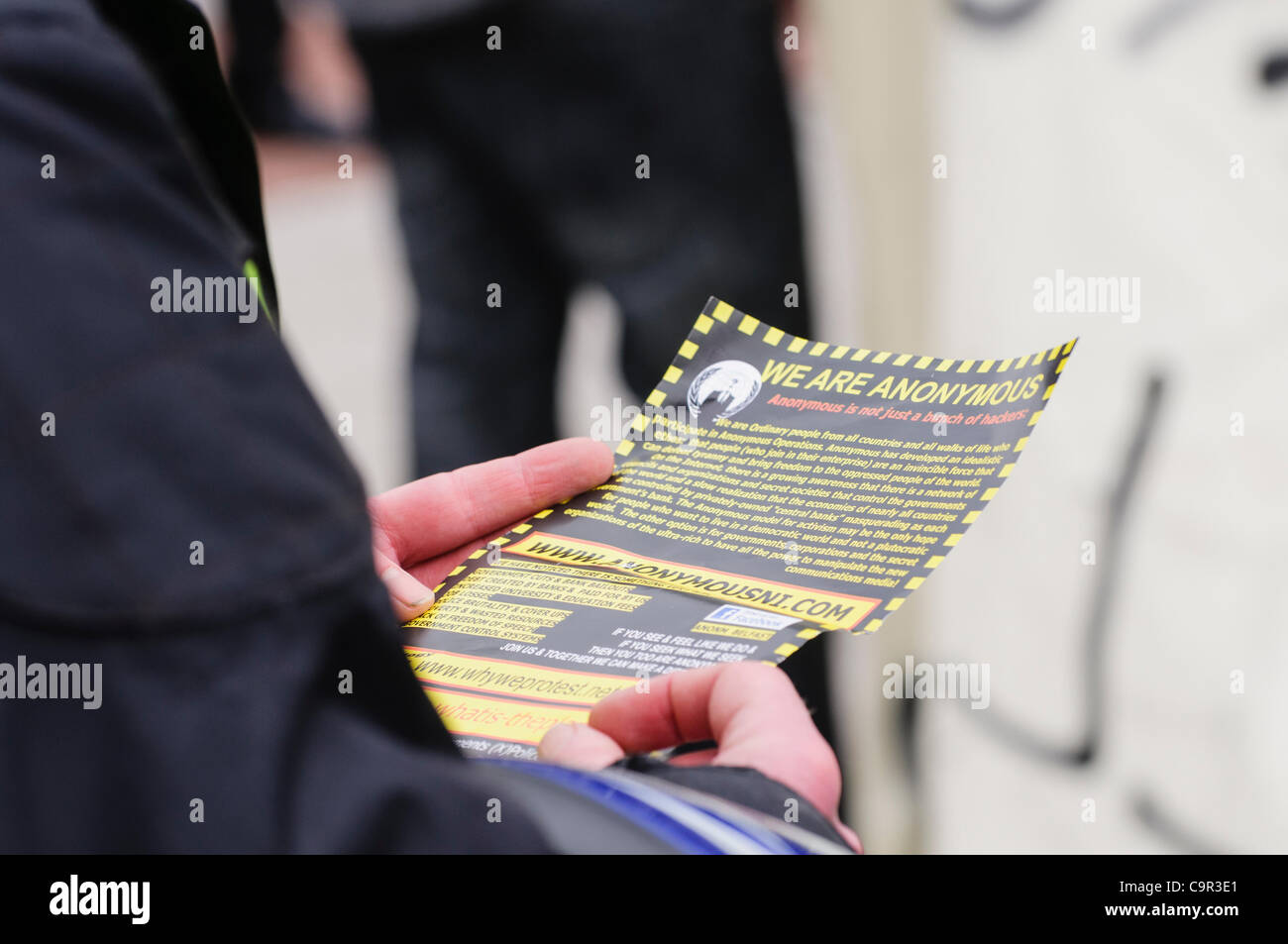 Uomo legge un opuscolo distribuito da un membro di 'Anonimo' di Belfast Foto Stock