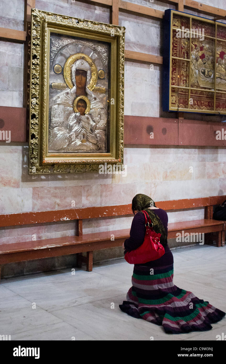 Una donna si inginocchia in preghiera prima di un'immagine di Cristo con la Vergine Maria come migliaia di pellegrini cristiani e credenti gregge, la Chiesa del Santo Sepolcro il Mercoledì delle Ceneri. Gerusalemme, Israele. 22-Feb-2012. Foto Stock