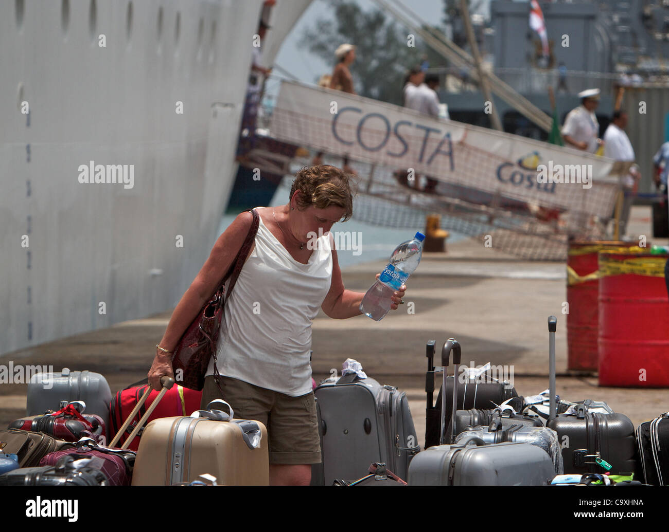 Marzo 01, 2012 - victoria Seychelles - un passeggero raccoglie i suoi bagagli dopo lo sbarco di Costa Allegra. L'italiano la nave di crociera è stato trainato in francese dalla profondità del mare tonno trawler sebbene più velocemente di un rimorchiatore era disponibile. Più di 1.000 passeggeri e membri di equipaggio sbarcò storpi Costa tutti Foto Stock