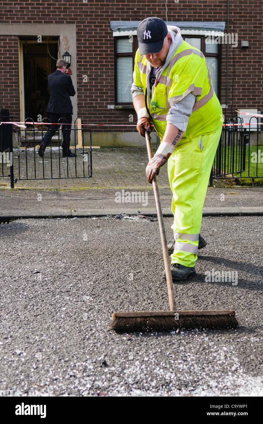 Belfast, Regno Unito. 10 mar 2012. Un lavoratore del consiglio vetro pennelli di una strada dopo un attentato alla bomba in una casa Foto Stock