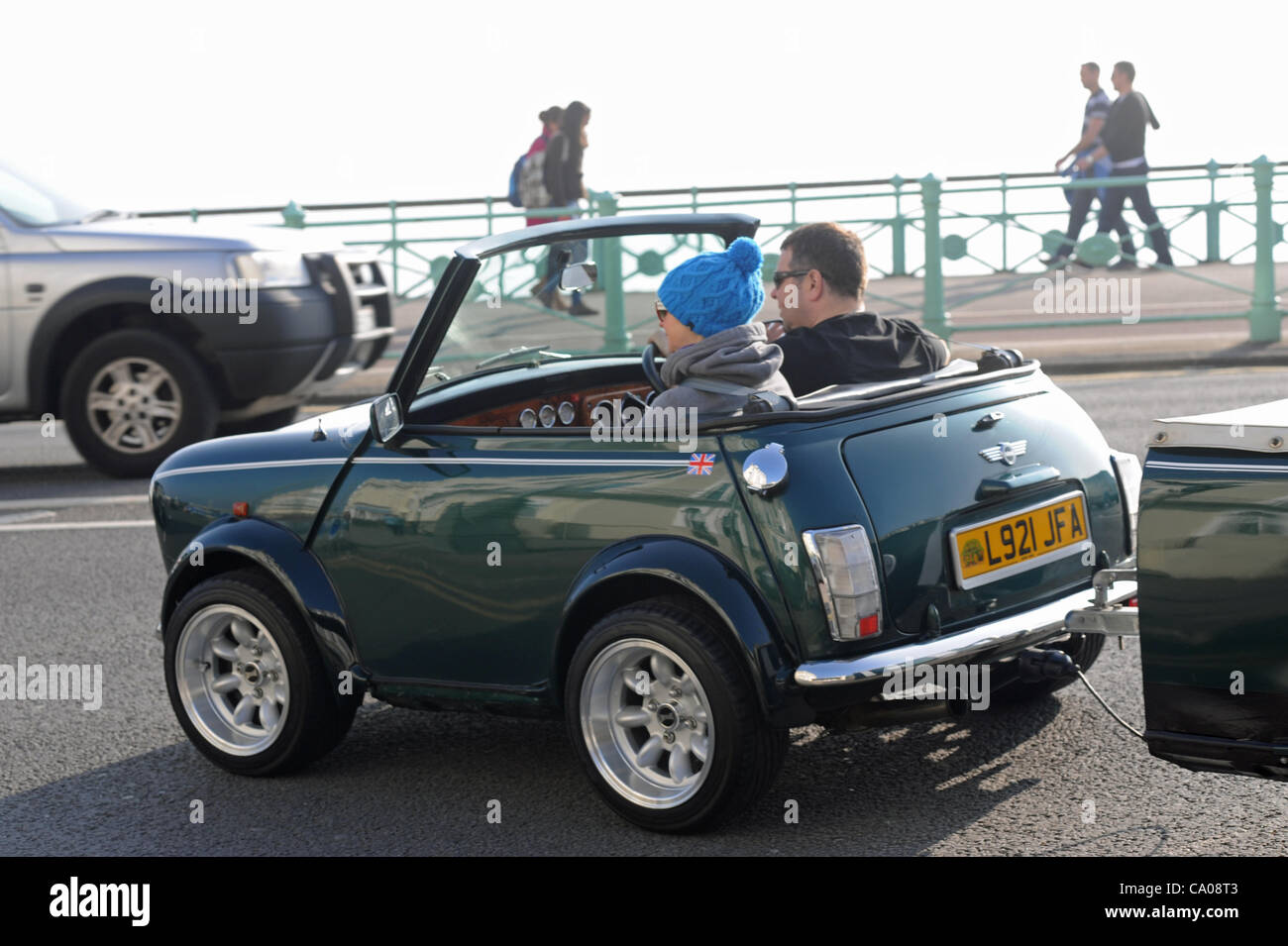 Brighton, Regno Unito. 12 mar 2012. Un paio di godere del tempo caldo sul lungomare di Brighton nel loro tagliata Mini con il suo tetto off. Credito: Simon Dack/Alamy Live News Foto Stock