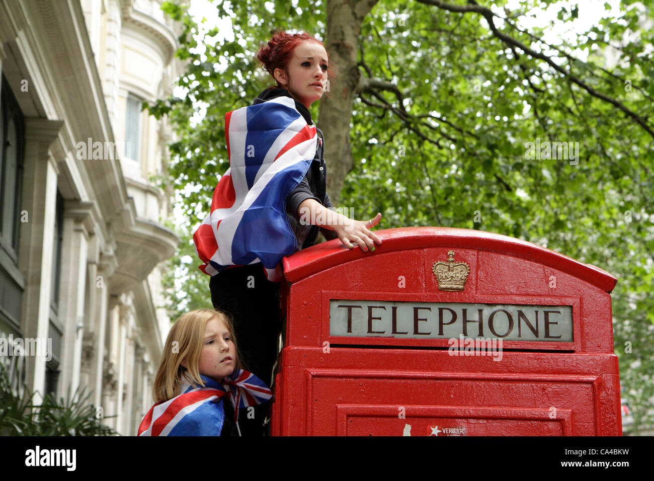 Due ragazze salire su di una cabina telefonica per guardare il diamante della regina carrello giubilare processione, Londra Foto Stock