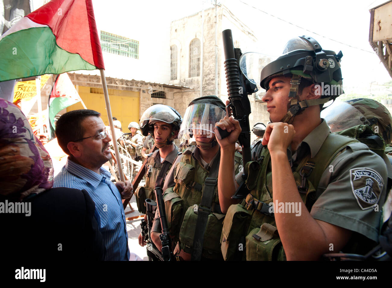 HEBRON, Territori palestinesi - Giugno 5, 2012: un uomo palestinese affronta pesantemente armati soldati israeliani in una manifestazione nonviolenta per commemorare la Naksa Day, l'anniversario dell'occupazione israeliana dei territori palestinesi nel 1967. Foto Stock