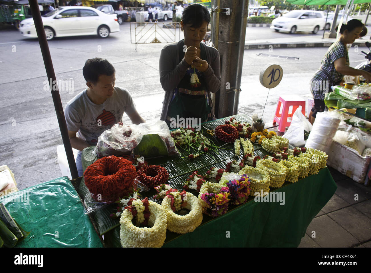 7 giugno 2012 - Bangkok, Thailandia - Flower venditori preparare ghirlande a Bangkok il mercato dei fiori di Giovedì, Giugno 7, 2012 nella capitale Thailandese. Thais usare il mentre ghirlande come offerta a statue buddiste e il loro colore bianco symbolizers la bellezza di gli insegnamenti del Buddha. Quando essi età, essi symboli Foto Stock