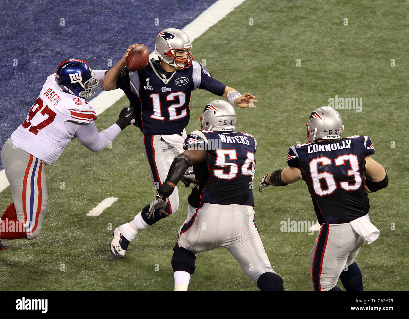 Febbraio 5, 2012 - Indianapolis NEGLI STATI UNITI - New England Patriots quarterback Tom Brady #12 ottiene subito pressioni da parte di New York Giants tackle difensivo Linval Joseph #97 durante il Super Bowl XLVI. Super Bowl XLVI è venuto giù per i secondi finali come New York Giants battere il New England Patriots con un punteggio finale Foto Stock