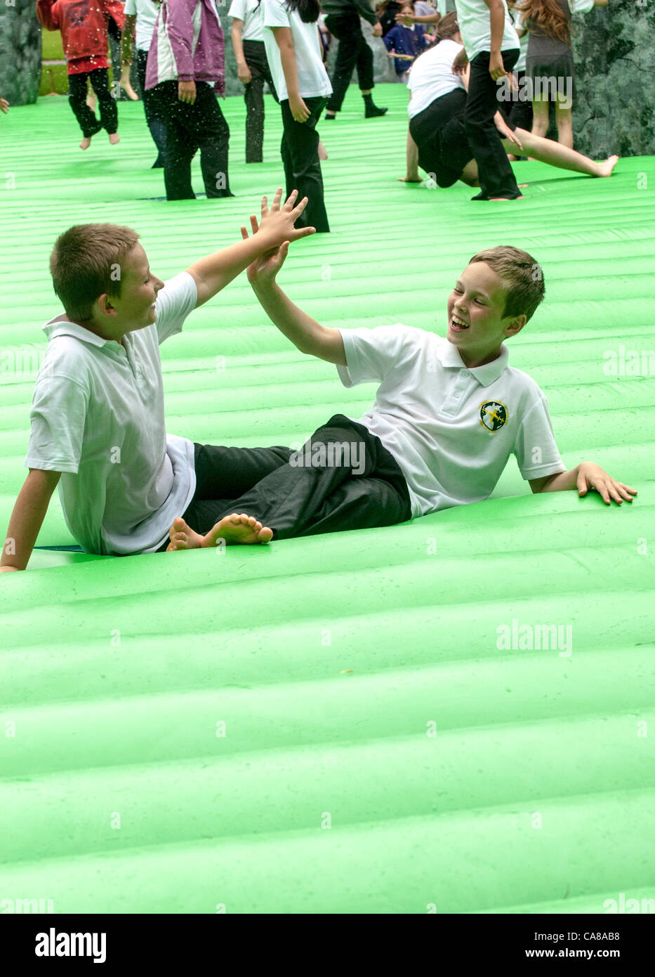 Due bambini in età scolare da St Sidwell della scuola di dare una elevata 5 sulla vita dimensioni replica gonfiabile di Stonehenge chiamato 'Sacrilege' Foto Stock