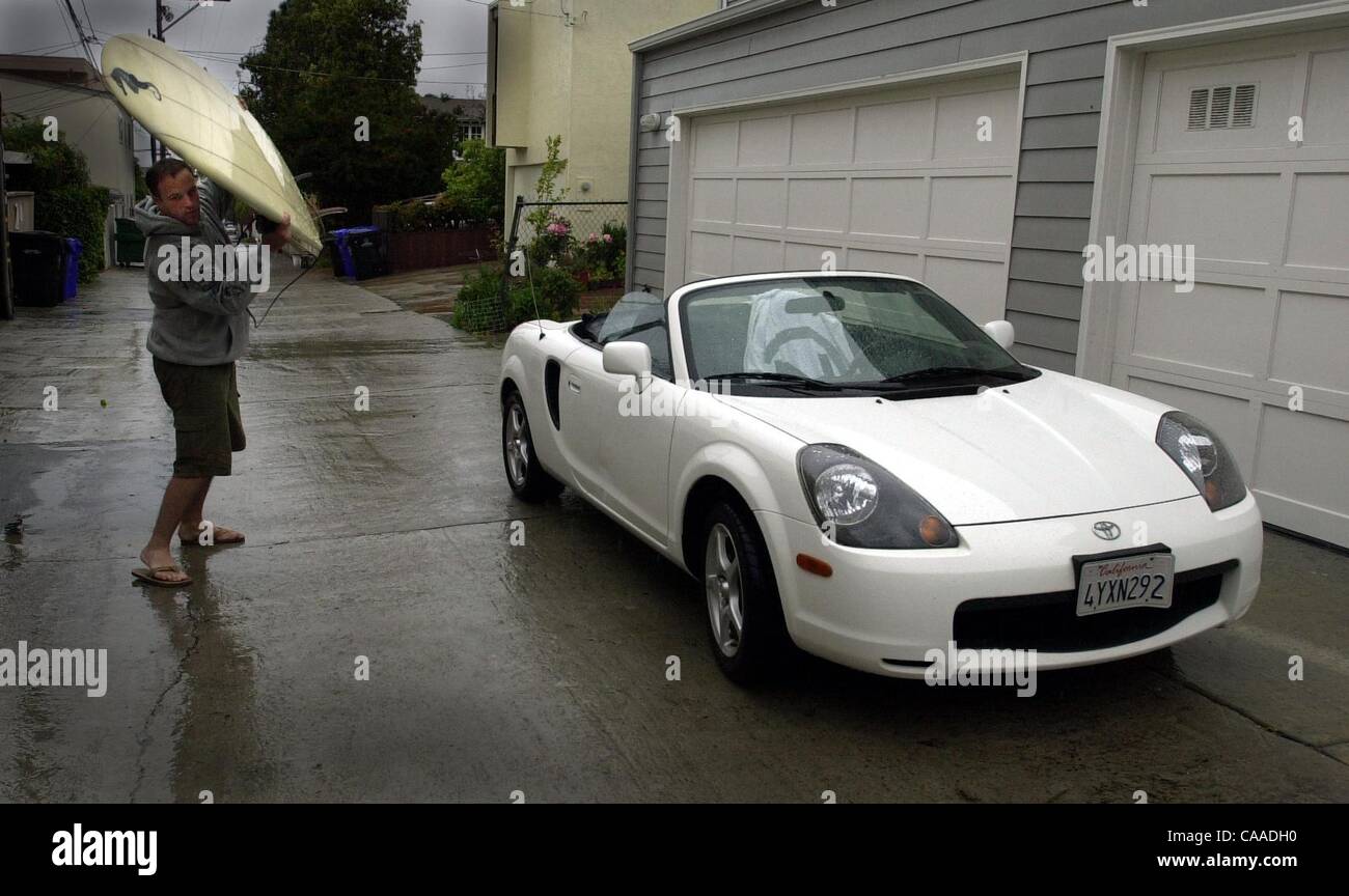 (Pubblicato il 4/18/2004, B-3; UTS1802287) La Jolla resident Brian Corbin, a sinistra si prende la sua tavola da surf a sua casa dopo il ritorno a casa nel suo convertibile aperta da Encinitas sotto la pioggia sabato mezzogiorno. Corbin, che era stato il surf con gli amici, detto ''una volta mi ha colpito Del Mar, è appena iniziato il versamento.'' Foto Stock