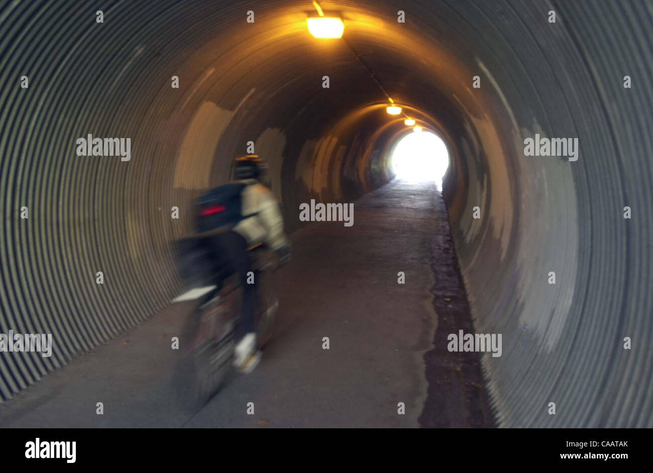 E la luce alla fine del tunnel --- una moto fa il suo modo attraverso un tunnel che passa sotto il North Main Street a Walnut Creek lungo il Contra Costa Canal sentiero regionale su un soleggiato e piovoso lunedì febbraio 2,2004. Venti forti e pioggia hit Contra Costa la maggior parte della mattinata con cieli soleggiati in Foto Stock