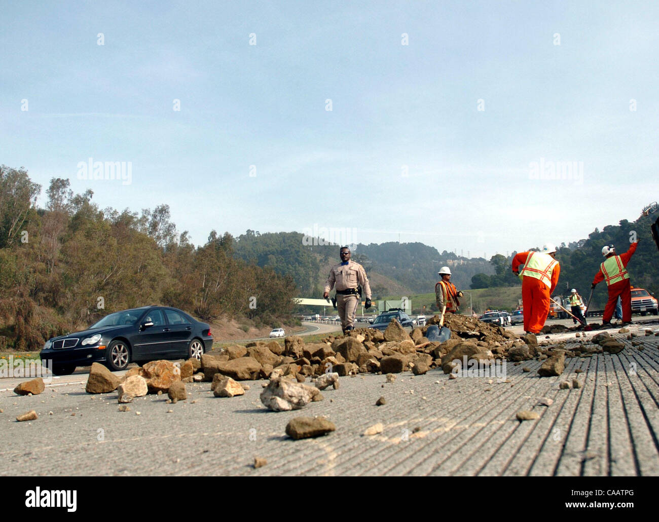 Il traffico è limitato a una corsia mentre gli equipaggi Caltrans ripulire il contenuto rimanente da un camion rovesciato su autostrada westbound 24 appena ad ovest del Caldecott in tunnel di Oakland, California, giovedì 6 febbraio 2004. (Dean Coppola/Contra Costa Times) Foto Stock