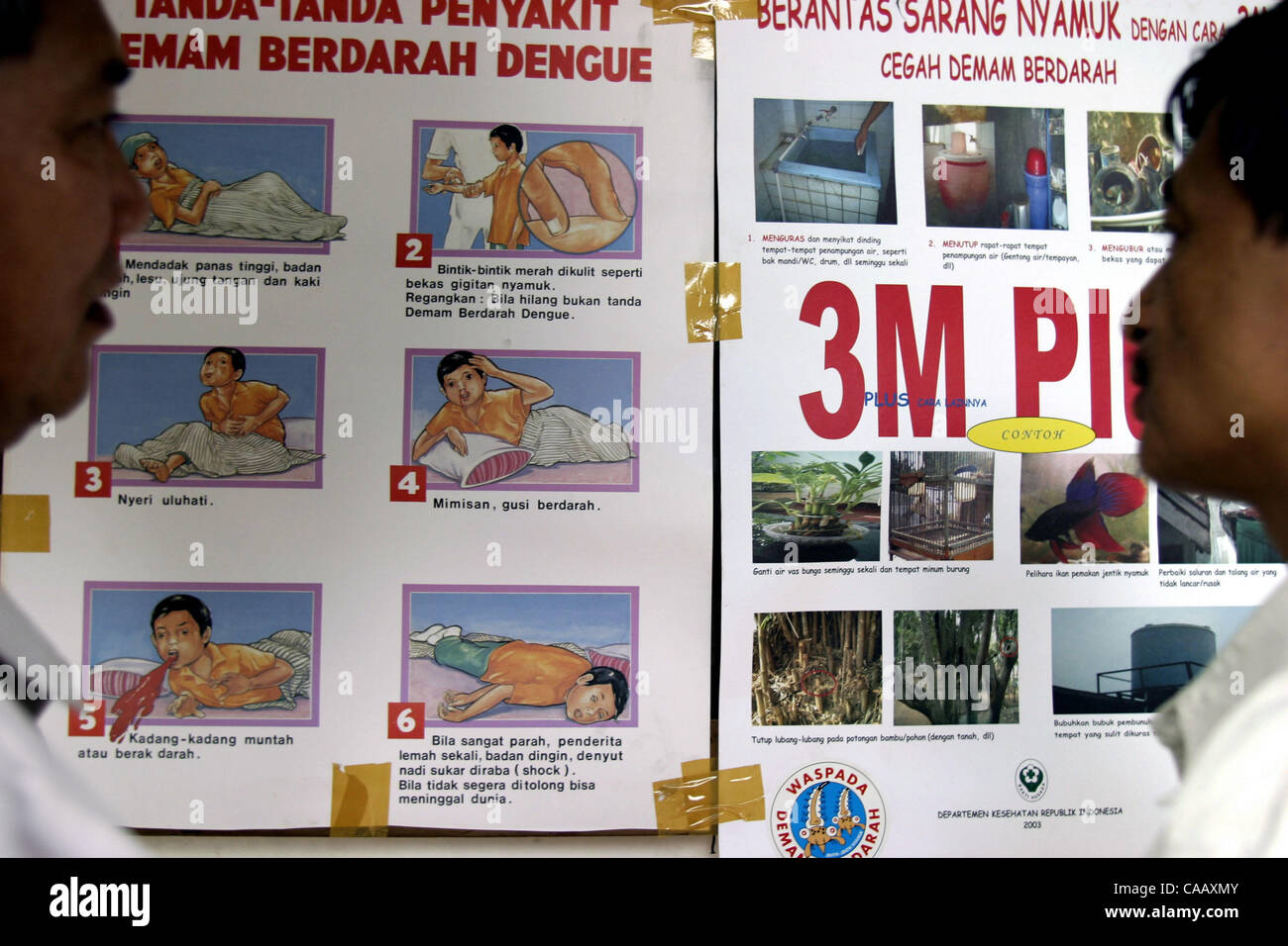 Marzo 1, 2004 JAKARTA, Indonesia due uomini leggere un poster di informazioni circa la febbre dengue rilasciato dal Ministero indonesiano di salute. Il corretto smaltimento dei rifiuti solidi e di acqua migliorato le pratiche di archiviazione, compresi contenitori di copertura per impedire l'accesso di uovo che posa zanzare femmina sono tra metop Foto Stock