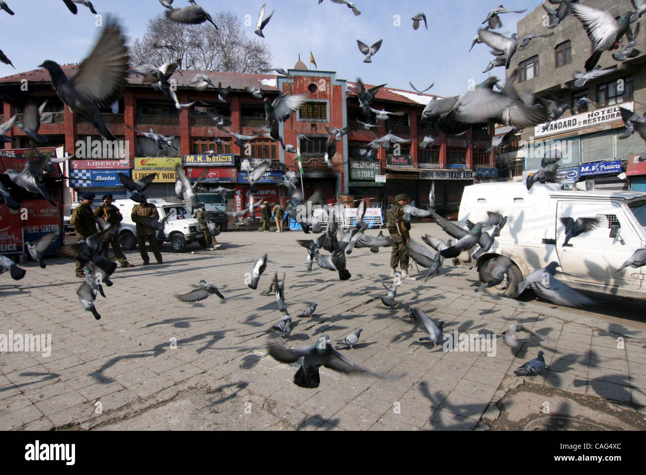 Indiano soldati paramilitari guardia dietro i battenti piccioni come negozi visto chiuso in Srinagar il 11 febbraio, 2008. La polizia in Kashmir indiano arrestate decine di dimostranti lunedì impegnativo i resti di Bhat, che fu impiccato e sepolto in un carcere indiano 24 anni fa, la polizia ha detto. Negozi Foto Stock