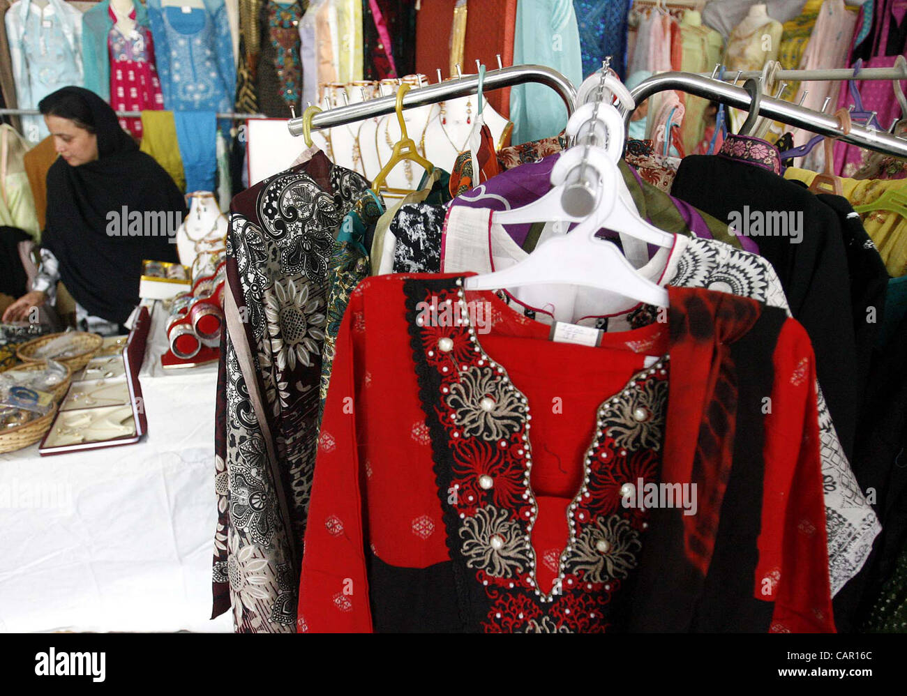 Una donna guarda i tessuti in una fase di stallo durante il Gala di primavera organizzato dalla organizzazione Razeens tenutasi a Peshawar Martedì, 10 aprile 2012. Foto Stock