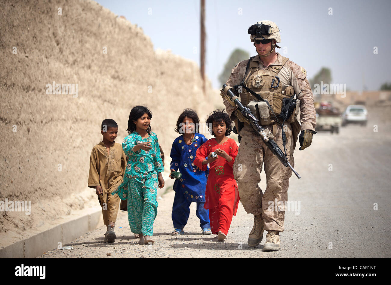 Bambini afgani camminare a fianco degli Stati Uniti Lancia Marine Cpl. Giacobbe Kartchner, leader di un team con il quarto plotone, Kilo Company, 3° Battaglione, 3° Reggimento Marine, e 28-anno-vecchio nativo di Long Beach, California come egli le pattuglie con Marines e afghane Guardia Nazionale Foto Stock