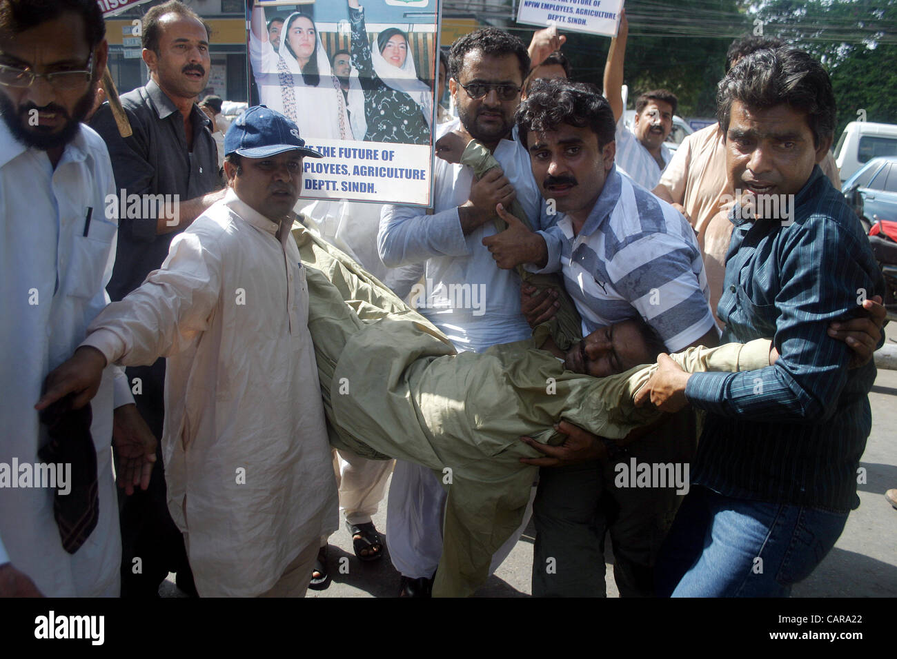 Commissione nazionale per lo sviluppo umano (NCHD) dipendenti tenere il loro collega che si sente in stato di incoscienza a causa di gas lacrimogeni, come polizia ha usato i gas lacrimogeni-gusci per disperdere i loro durante la manifestazione di protesta per i lavori regolari a Karachi press club il giovedì 12 aprile, 2012. Foto Stock
