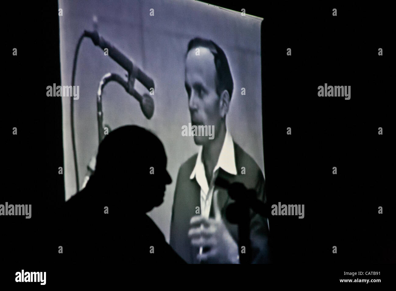 Silhouette di Yosef Kleinman, 82, superstite dell' Olocausto, come un clip filmato è proiettata del suo 1961 testimonianza nel processo di Adolf Eichmann, alla Sinagoga Bereshit alla vigilia dell Olocausto dei martiri ed eroi' giorno del ricordo. Bet-Shemesh, Israele. 18-Apr-2012. Foto Stock