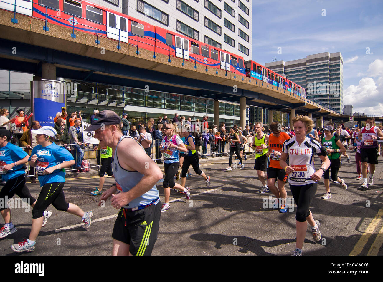 Londra, Canary Wharf, nei pressi di miglio 18, 22 aprile 2012, concorrenti nella maratona di Londra 2012 hanno quasi dieci chilometri in più per andare come la Docklands Light Railway (DLR) passa le guide. Foto Stock