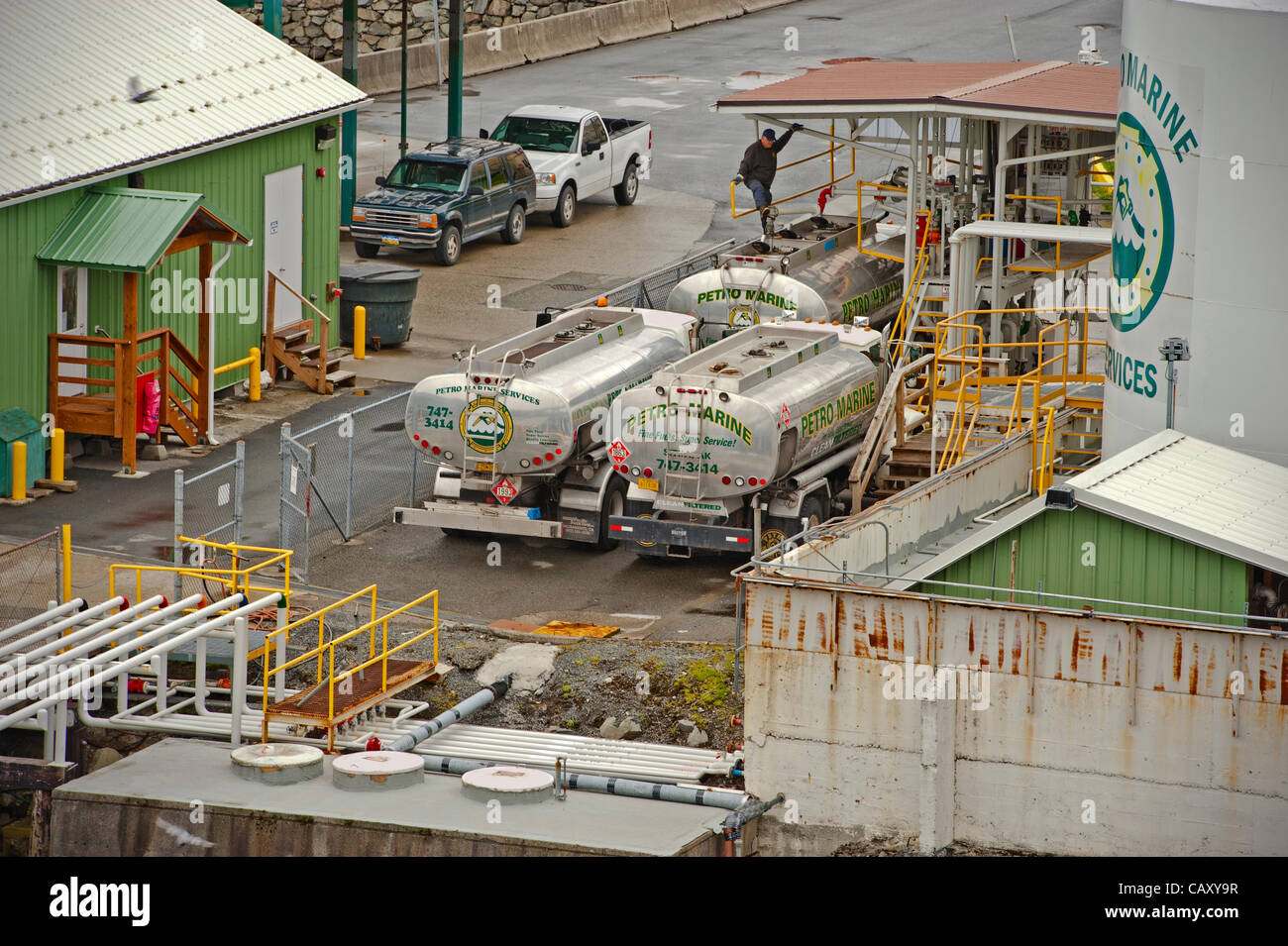 Sitka, Alaska, 5 maggio 2012 camionista si rilassa durante il rifornimento di carburante il suo autocisterna con benzina. Foto Stock