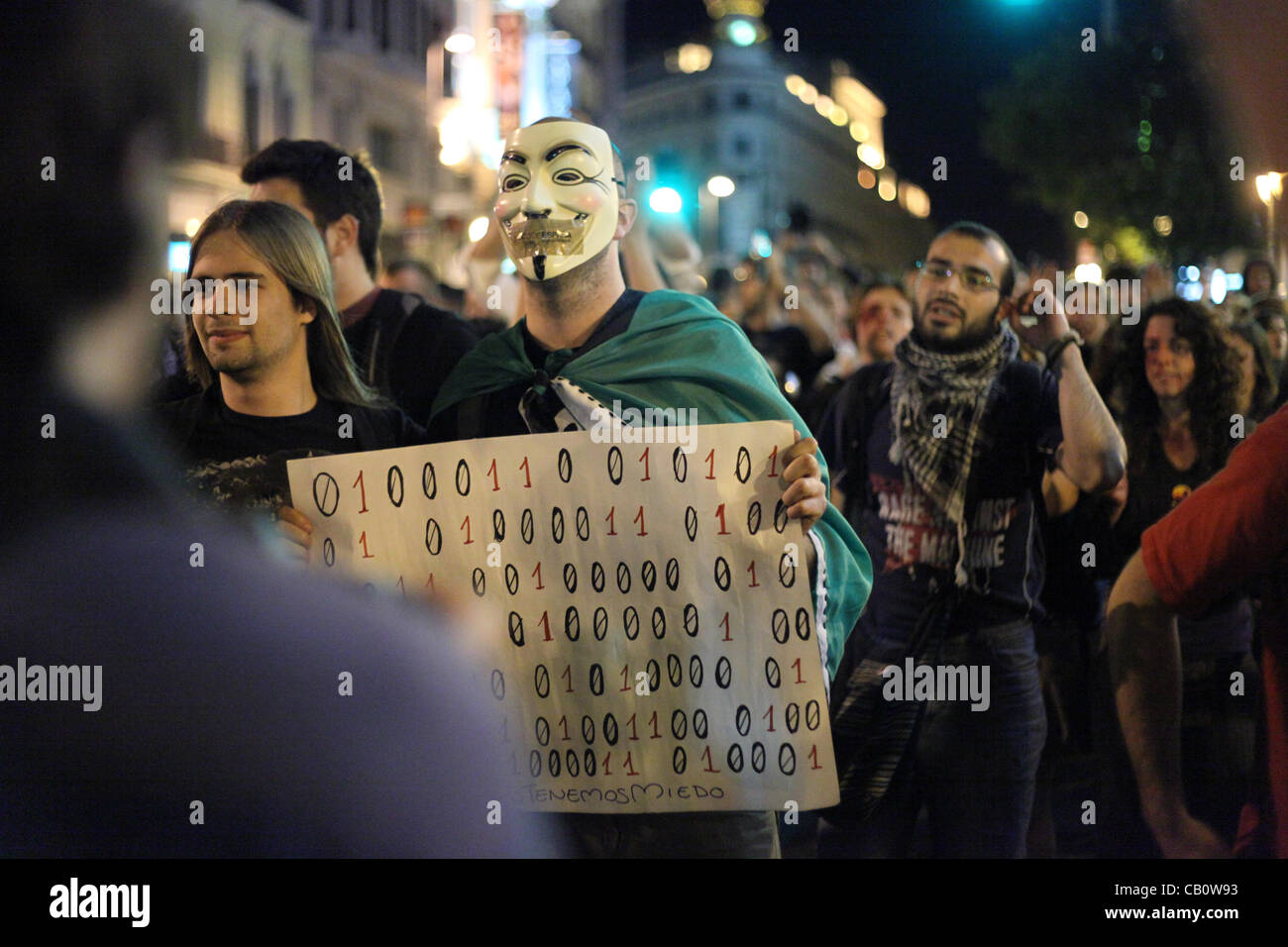 Madrid, Spagna. Un uomo che indossa un ragazzo Fox maschera con nastro adesivo che copre la sua bocca cammina con una folla enorme di manifestanti da Puerta del Sol al Banco de España il 15 maggio 2012. Questa protesta segnato un anno anniversario della Spagna Indignado del movimento che ha scatenato simile occupare movimenti intorno al globo. Foto Stock