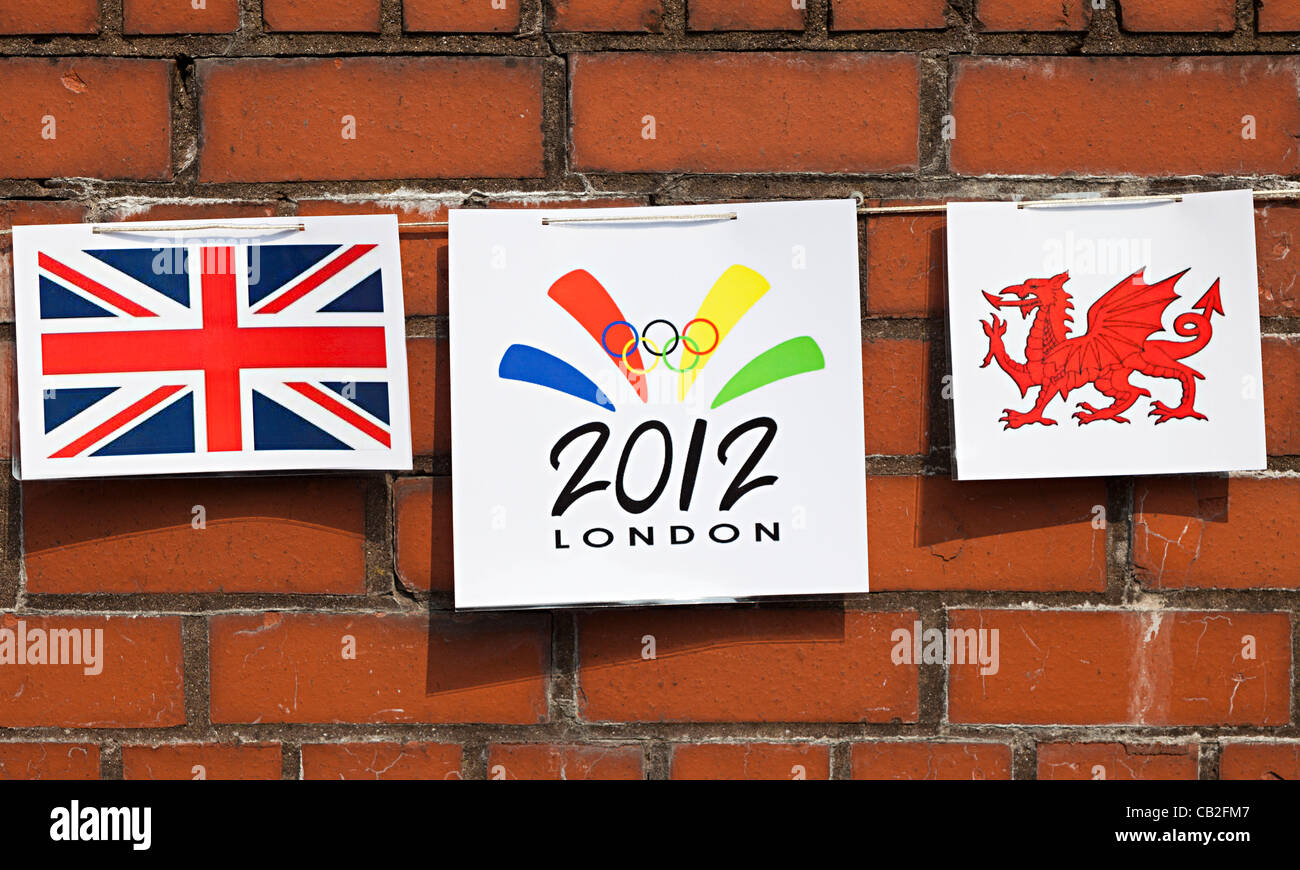 Le bandiere e gli emblemi in bunting su un rosso muro di mattoni sulla rotta per il 2012 torcia olimpica attraversano la città di Abergavenny, Wales, Regno Unito, ha luogo il venerdì 25 maggio 2012. Pavese è stato messo davanti a caso Foto Stock