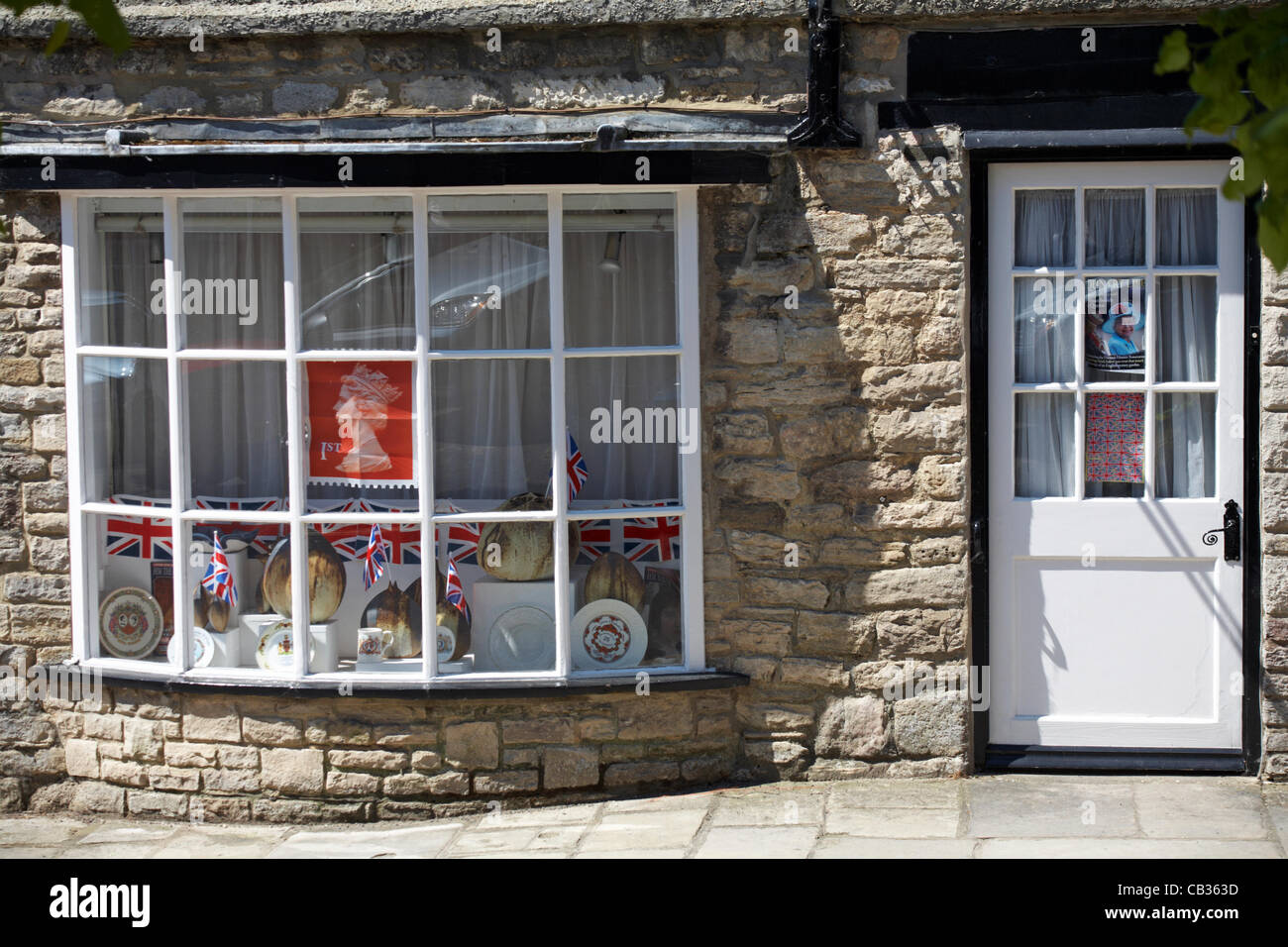 Preparazione per la regina il Sessantesimo giubileo di diamante a Corfe Castle, DORSET REGNO UNITO - royal memorabilia, francobolli e Union Jack Flag nella finestra Foto Stock