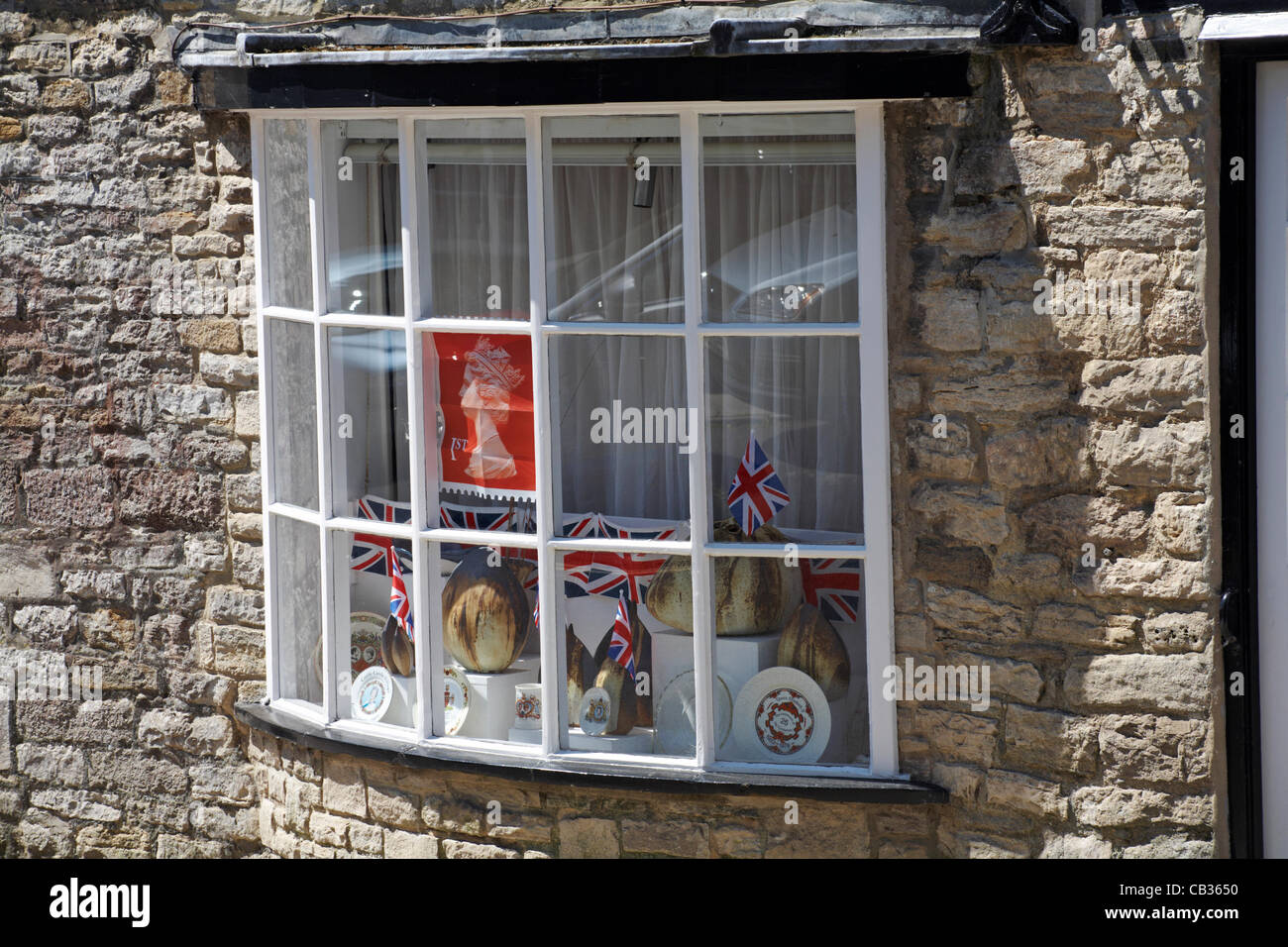 Preparazione per la regina il Sessantesimo giubileo di diamante a Corfe Castle, DORSET REGNO UNITO - royal memorabilia, francobolli e Union Jack Flag nella finestra Foto Stock