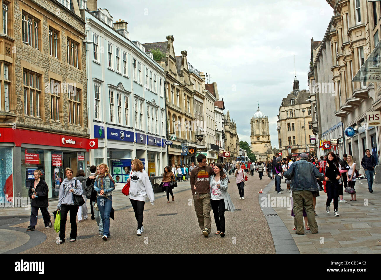 Gli amanti dello shopping nella zona pedonale, Cornmarket Street, Oxford, con Tom Torre del Christ Church College in background Foto Stock