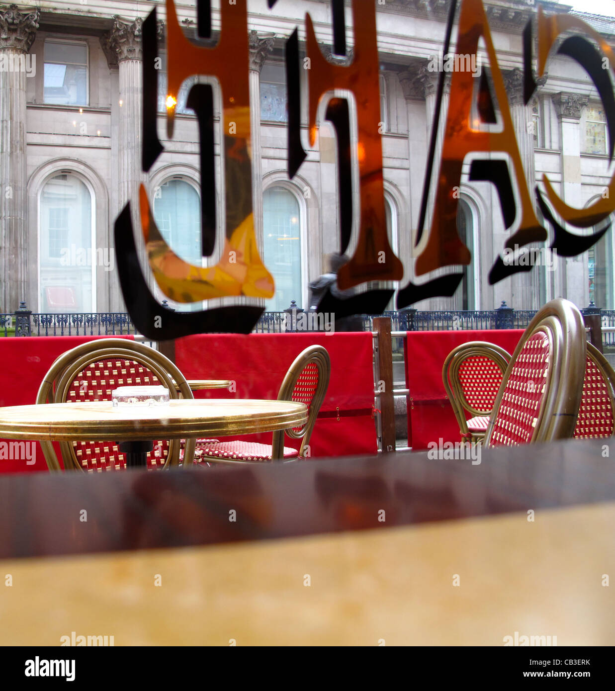 Scena dalla finestra caffetteria guardando attraverso il segno per tavoli all aperto Foto Stock