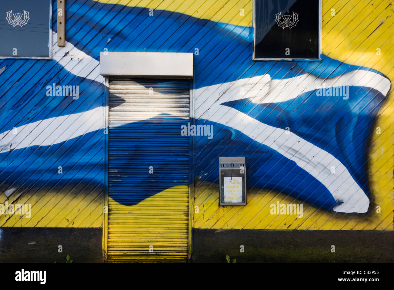 Una spruzzata croce di Sant'Andrea bandiera della Scozia vola attraverso la parete e l'otturatore della chiusura di un bar nel sud di Glasgow Goven Hill. Foto Stock