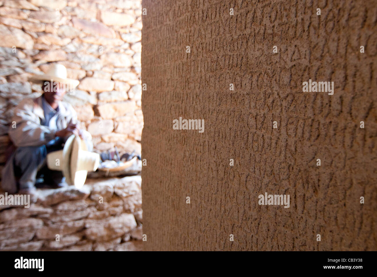 Un custode si siede accanto a re Ezana di iscrizione presso le tombe dei re Kaleb e Gebre Meskel in Aksum, Nord dell'Etiopia. Foto Stock