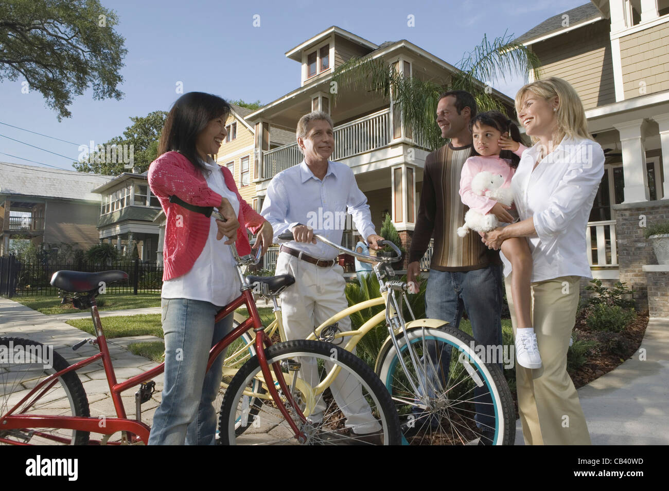 Famiglia con bambino conversando con i vicini di casa di fronte a casa Foto Stock