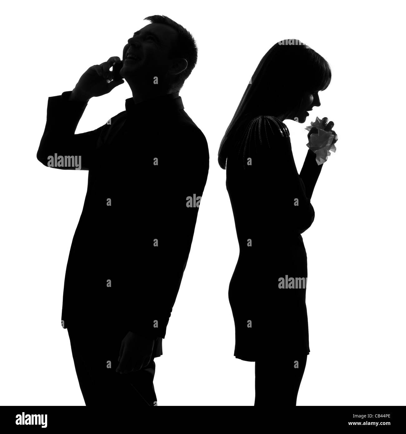 Una coppia caucasica in piedi di schiena Uomo al telefono e la donna che piange in studio silhouette isolati su sfondo bianco Foto Stock