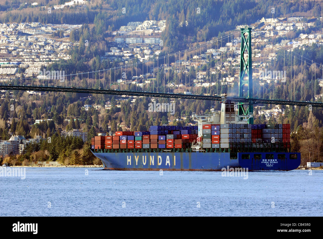 Contenitore di carico freighter uscendo Vancouver porto interno sotto il Ponte Lions Gate. Foto Stock