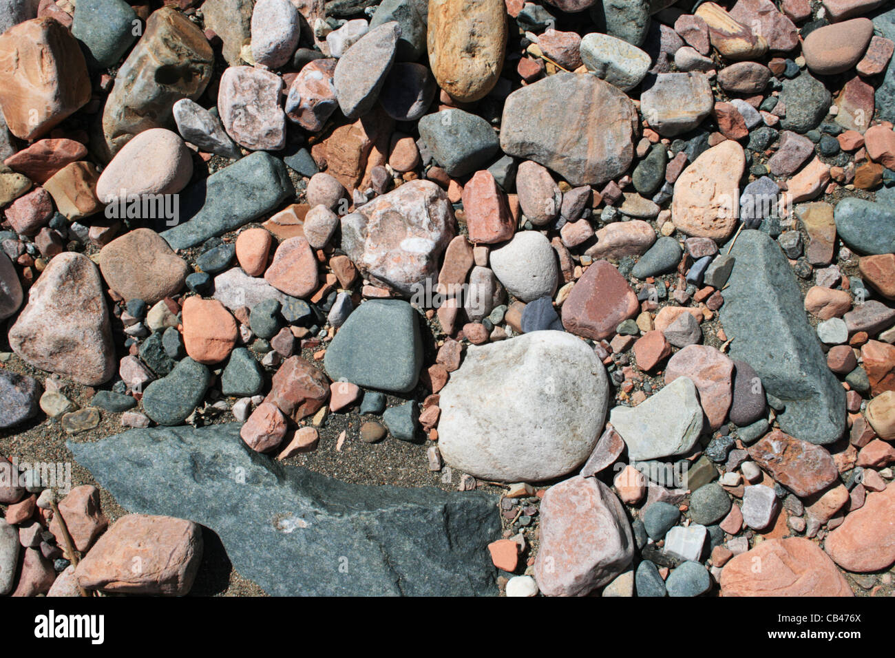 Lisci arrotondati grigio, bianco e il Red Rock e Sfondo sabbia Foto Stock