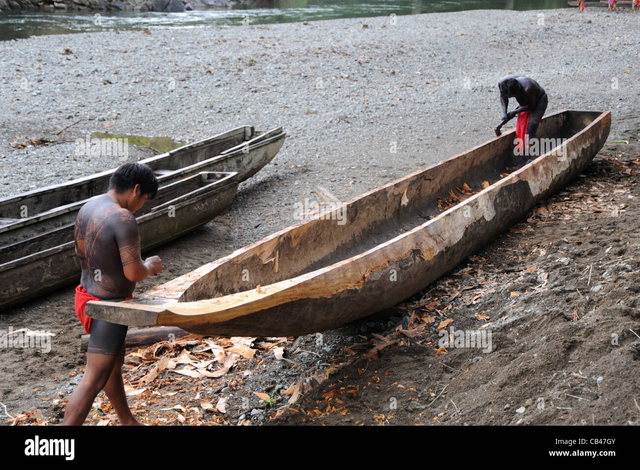 Gli uomini di Embera usano un'ascia a mano per incavare e modellare un cayuco. Gli indigeni di Embera hanno fatto uscire un tronco di albero per costruire e formare questo tipo di canoa di legno. Foto Stock
