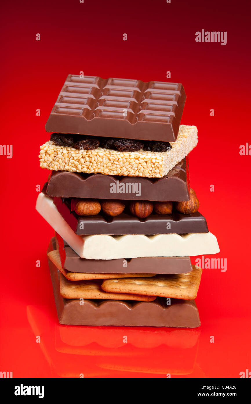 Pila di cioccolato e alcune altre cose dolci su rosso Foto Stock