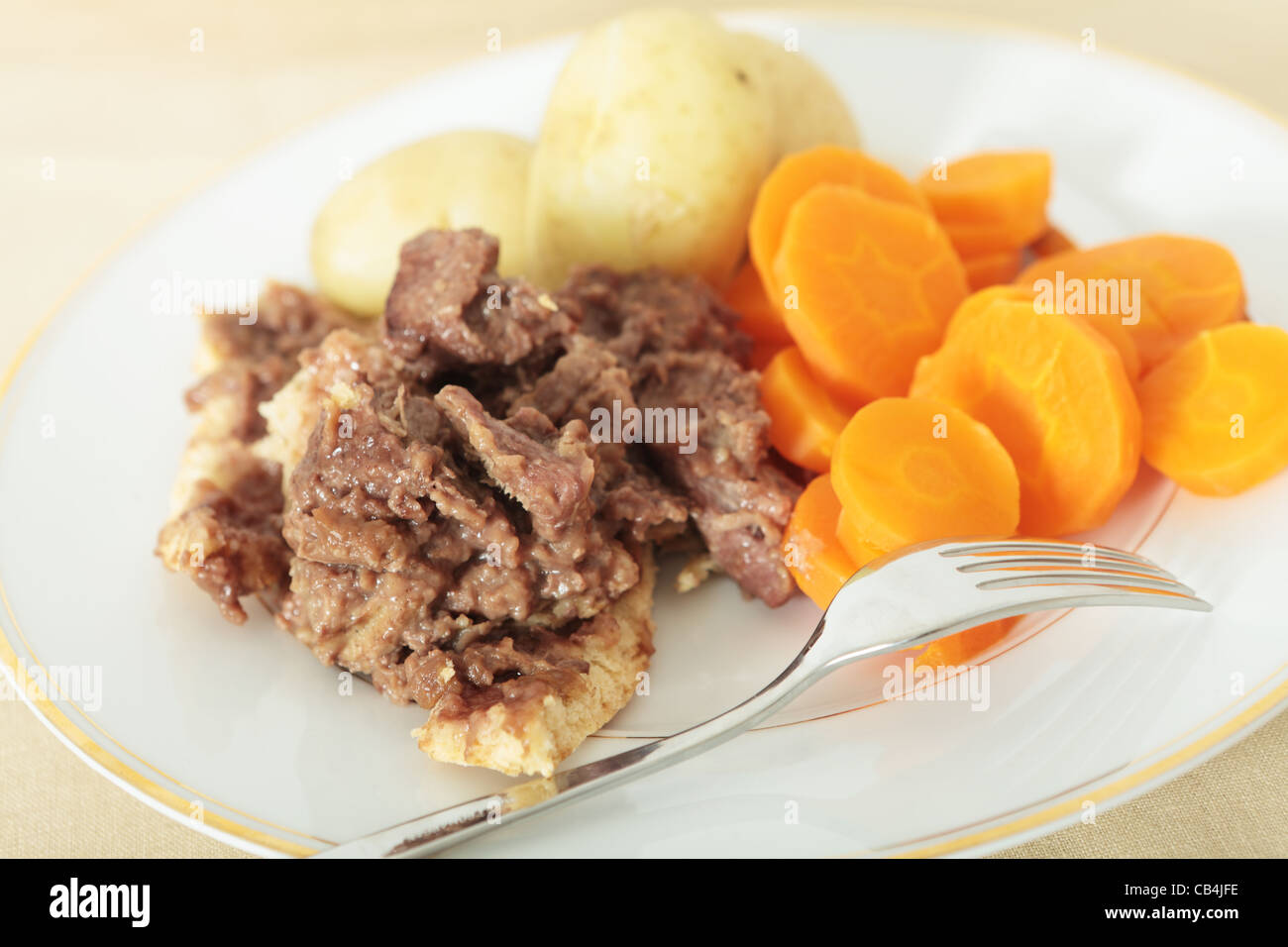 Un pasto a base di bistecche e rene pudding servito con patate novelle bollite e fette di carota Foto Stock