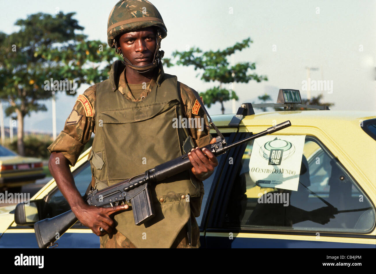 Conferenza delle Nazioni Unite su ambiente e sviluppo, Rio de Janeiro, Brasile, 3° al 14 giugno 1992. Un brasiliano Marine in uniforme con il suo fucile da un Rio taxi con un Rio 92 poster nella finestra . Foto Stock