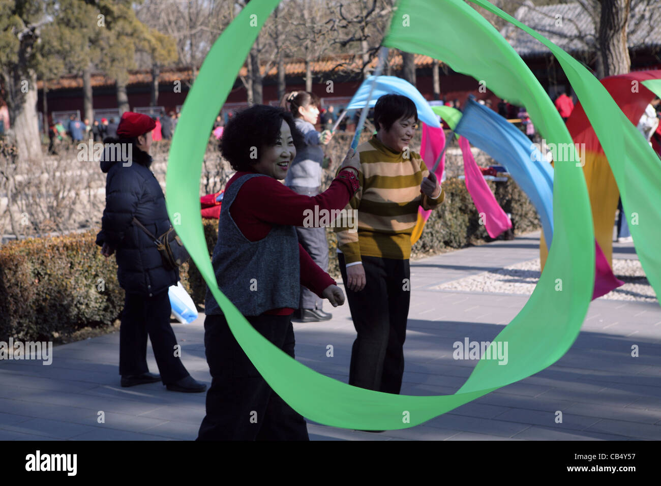 Ordinario di donne cinesi godono di attività di gruppo in park di Pechino, Cina, ginnastica ritmica fa roteare a nastro Foto Stock