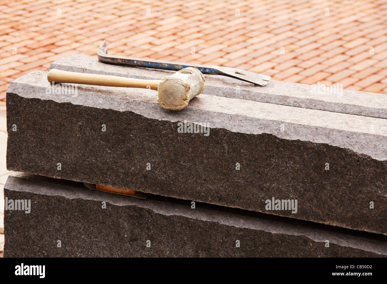 I blocchi di granito con un mazzuolo e piede di porco in appoggio sulla parte superiore. Foto Stock