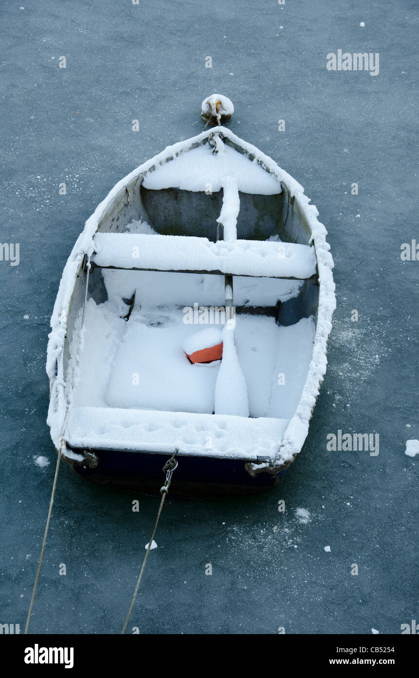 Un piccolo dinghy in legno ricoperta di neve e circondato da ghiaccio nel porto di Whitehaven, Cumbria, Inghilterra. Foto Stock