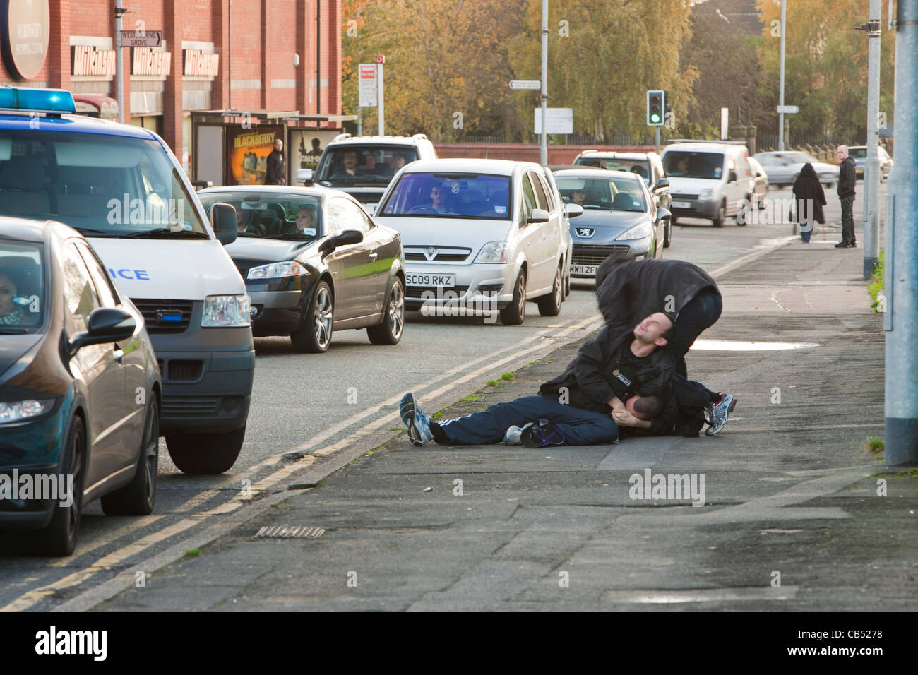 La polizia di affrontare un negozio lifter a Manchester e combattiamo lui a terra. Foto Stock