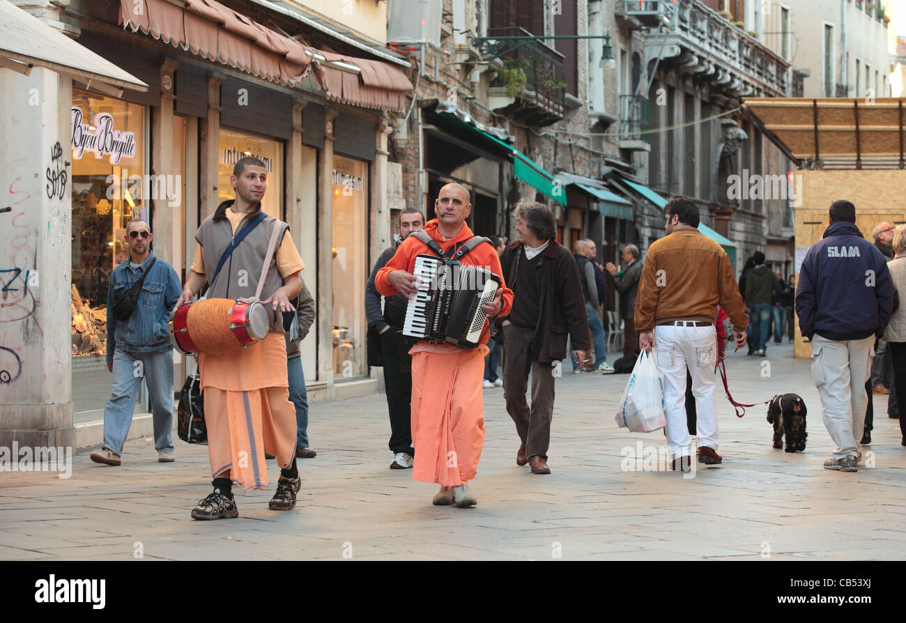 I seguaci di Hare Krishna setta di eseguire musica religiosa e dei canti come essi a piedi attraverso la zona commerciale di venezia, Italia Foto Stock