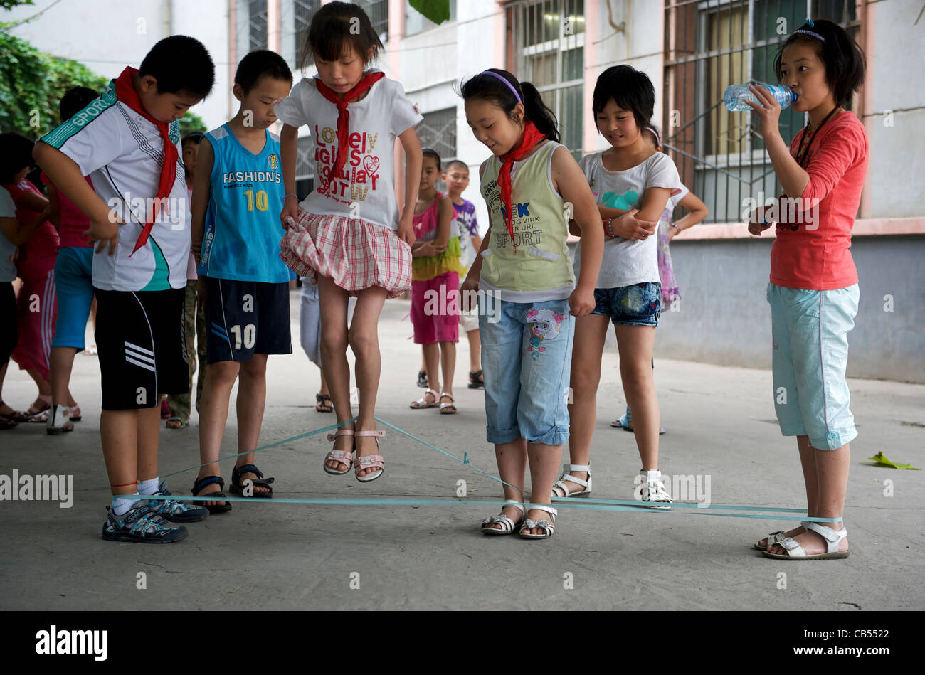 Il cinese gli studenti giocano a salto con la corda durante la pausa in una scuola primaria in Xian, provincia di Shaanxi, Cina. 20-giu-2011 Foto Stock