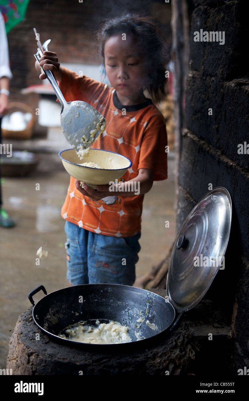 Un soggiorno-at-home ragazza riempie una ciotola di riso per il pranzo in remoto di poveri Tumen village, Shangluo, nella provincia di Shanxi, Cina. 21-giu-2011 Foto Stock
