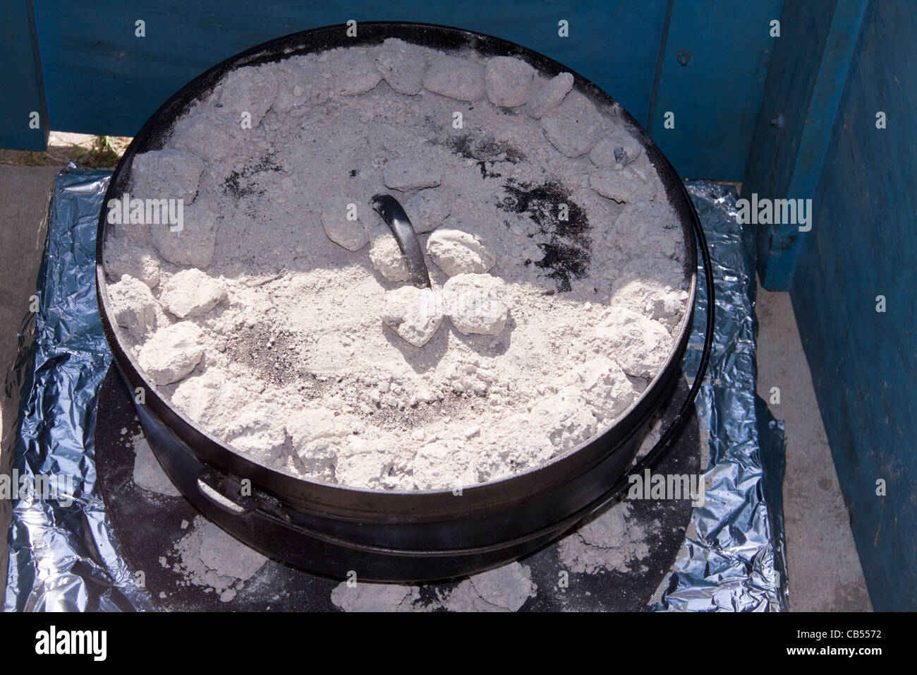 Forno olandese cucina outdoor utilizzando bicchieri impilati con base in metallo e i supporti in casa il parabrezza per proteggere carboni ardenti dal vento. Foto Stock